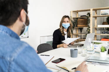 Business people wearing protective masks working in office  - GIOF10418