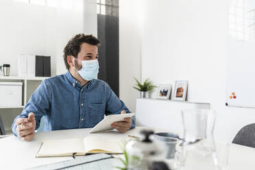 Man wearing protective mask working in office  - GIOF10420