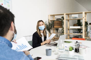 Business people wearing protective masks working in office  - GIOF10424