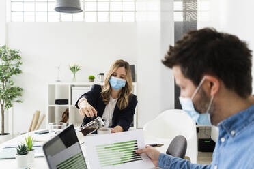 Business people wearing protective masks working in office  - GIOF10426