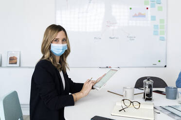 Portrait of business woman wearing protective mask working in office  - GIOF10428