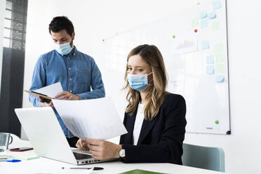 Business people wearing protective masks working in office  - GIOF10434