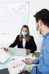 Business people wearing protective masks working in office  - GIOF10439