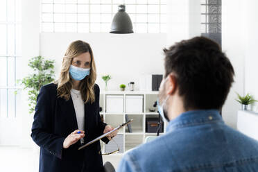 Geschäftsleute mit Schutzmasken bei der Arbeit im Büro - GIOF10440