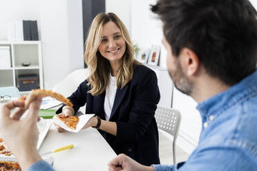 Business people eating pizza and talking in office during break - GIOF10453