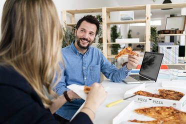 Geschäftsleute, die in der Pause Pizza essen und sich im Büro unterhalten - GIOF10454