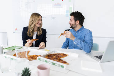 Business people eating pizza and talking in office during break - GIOF10455