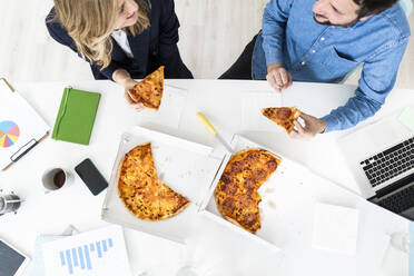 Geschäftsleute, die in der Pause Pizza essen und sich im Büro unterhalten - GIOF10457