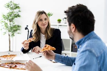 Geschäftsleute, die in der Pause Pizza essen und sich im Büro unterhalten - GIOF10460