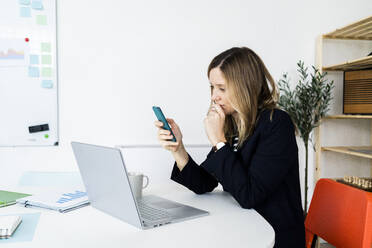 Business woman using smart phone in office - GIOF10502