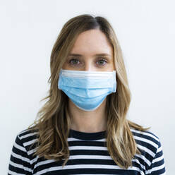 Studio portrait of woman wearing face mask - GIOF10514