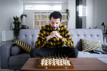 Mann sitzt auf einem Sofa vor einem Schachbrett - GIOF10518