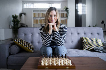 Porträt einer Frau, die auf einem Sofa vor einem Schachbrett sitzt - GIOF10519