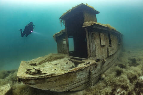 Scuba diver swimming toward shipwreck sunken in Lake Atter stock photo