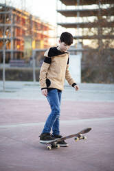 Männlicher Skateboarder fährt und übt Skateboard in der Stadt im Freien - CAVF91567