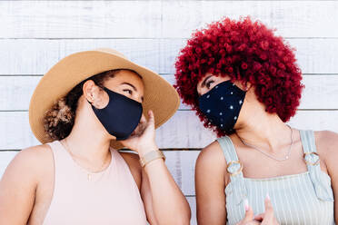 Zwei lateinische Frauen mit Maske in einer sorglosen Haltung auf einem weißen Hintergrund - CAVF91580