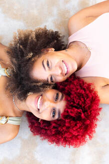 Zenithales Porträt zweier lateinamerikanischer Frauen mit Afro-Haar auf dem Boden. - CAVF91582