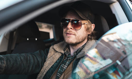 Mann mit Sonnenbrille im Auto sitzend durch Fenster gesehen - JCCMF00625