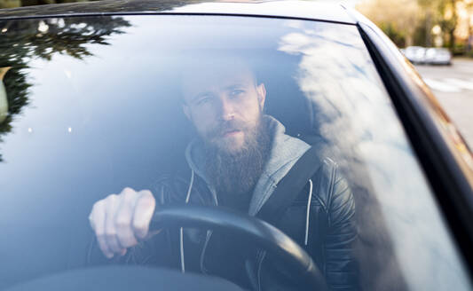 Bärtiger Mann am Steuer eines Autos durch die Windschutzscheibe gesehen - JCCMF00636