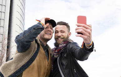 Bärtiger Mann nimmt Selfie mit Freund, während er gegen den Himmel steht - JCCMF00669