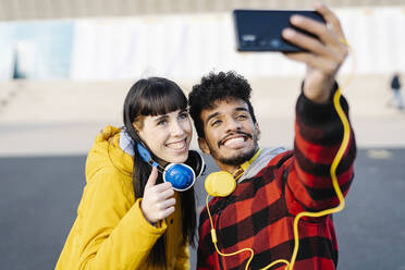 Junger Mann nimmt Selfie durch Handy mit weiblichen Freund, während im Freien stehen - JCZF00425
