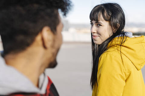 Smiling woman looking at male friend while standing outdoors stock photo