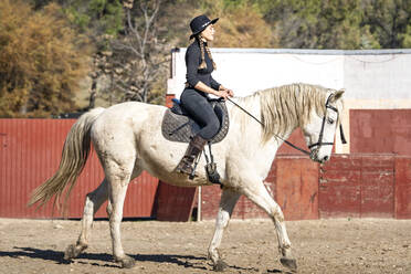 Woman horseback riding in paddock - GGGF00759