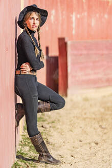 Portrait of female rancher leaning against fence - GGGF00775