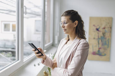 Geschäftsfrau benutzt Smartphone im Büro - GUSF04951