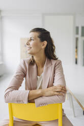 Smiling businesswoman sitting on chair in office - GUSF04985