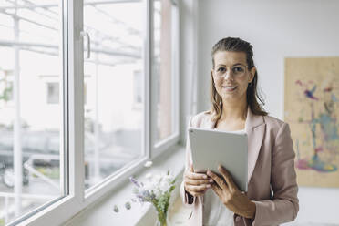 Portrait of smiling businesswoman with digital tablet in office - GUSF04988