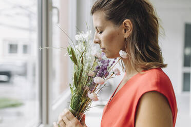 Frau riecht an Blumen am Fenster - GUSF05007