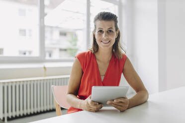 Porträt einer Geschäftsfrau mit digitalem Tablet im Büro sitzend - GUSF05017