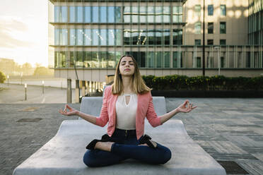 Spain, Barcelona, Young businesswoman meditating in city - XLGF00964