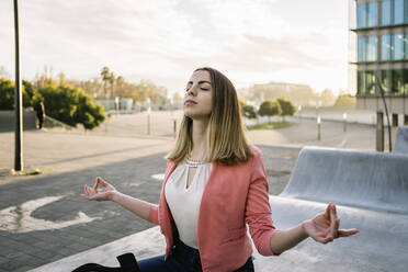 Spain, Barcelona, Young businesswoman meditating in city - XLGF00965