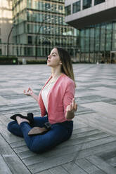 Spain, Barcelona, Young businesswoman meditating in city - XLGF00967