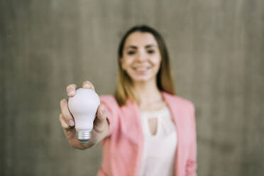 Portrait of young businesswoman holding light bulb - XLGF00969