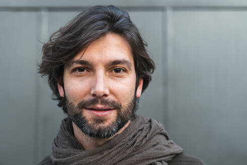 Portrait of man wearing scarf in front of gray wall - JMPF00769