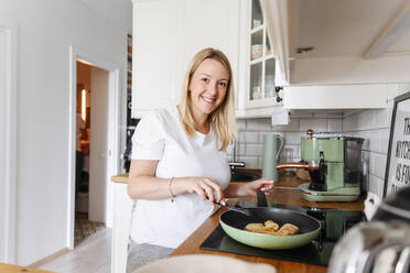 Portrait of smiling woman cooking - VYF00378