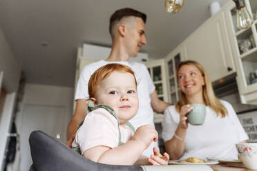 Happy family with baby daughter at kitchen table - VYF00384