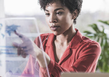 Woman pointing at transparent display at home - UUF22466