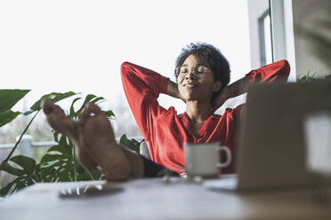 Woman relaxing with bare feet on desk - UUF22477