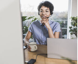 Woman sitting in front of computer, having video conference - UUF22481