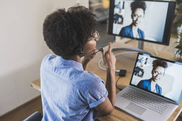Frau hält Videokonferenz mit Kollegen über Laptop zu Hause - UUF22492