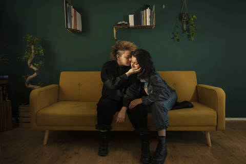 Lesbian couple kissing on sofa stock photo