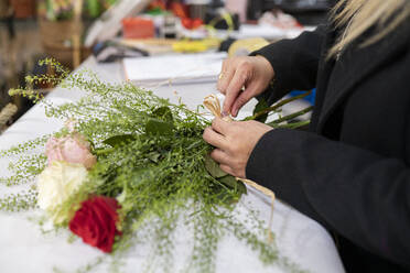 Florist bindet Blumenstrauß im Blumenladen - JCCMF00699