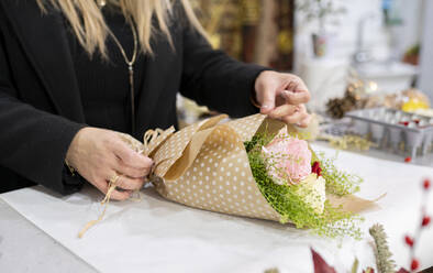 Florist wickelt Blumenstrauß mit Papier im Blumenladen ein - JCCMF00702