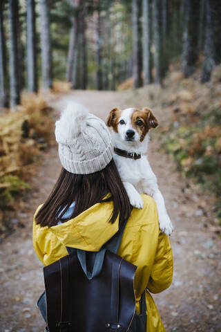 Woman carrying dog in forest stock photo