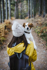 Woman carrying dog in forest - EBBF02111