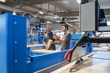 Two male carpenters talking in production hall - DIGF14163